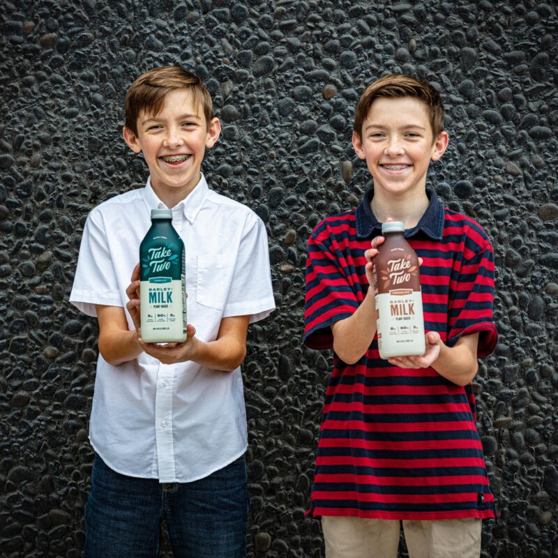 Twins holding Take Two Barley Milk bottles