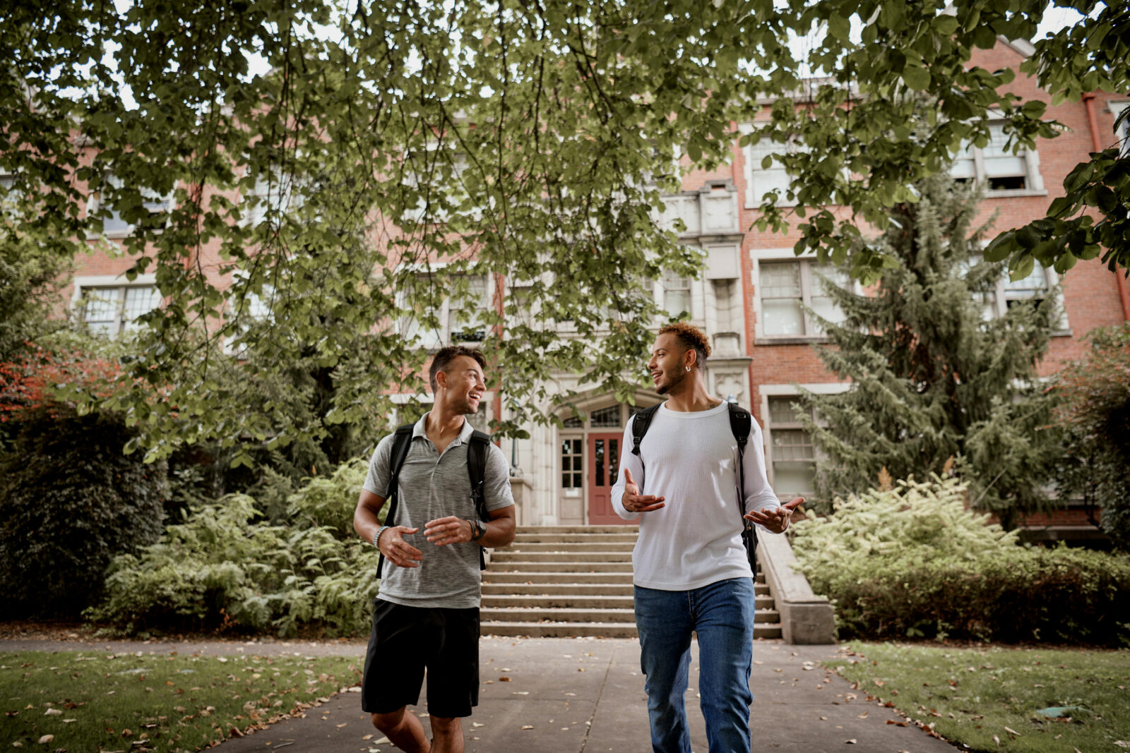 two students outside a building with backpacks on